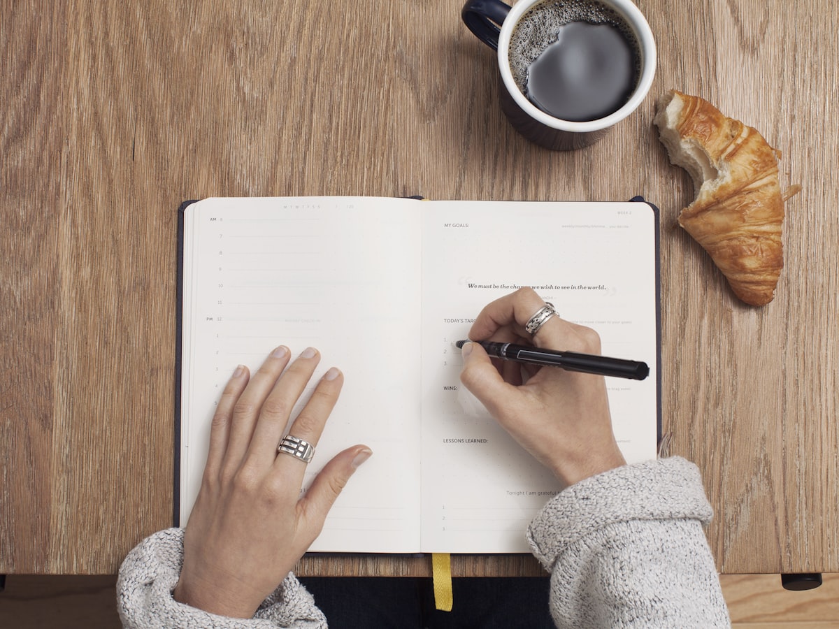Un journal ouvert, un stylo et un café sur une table en bois